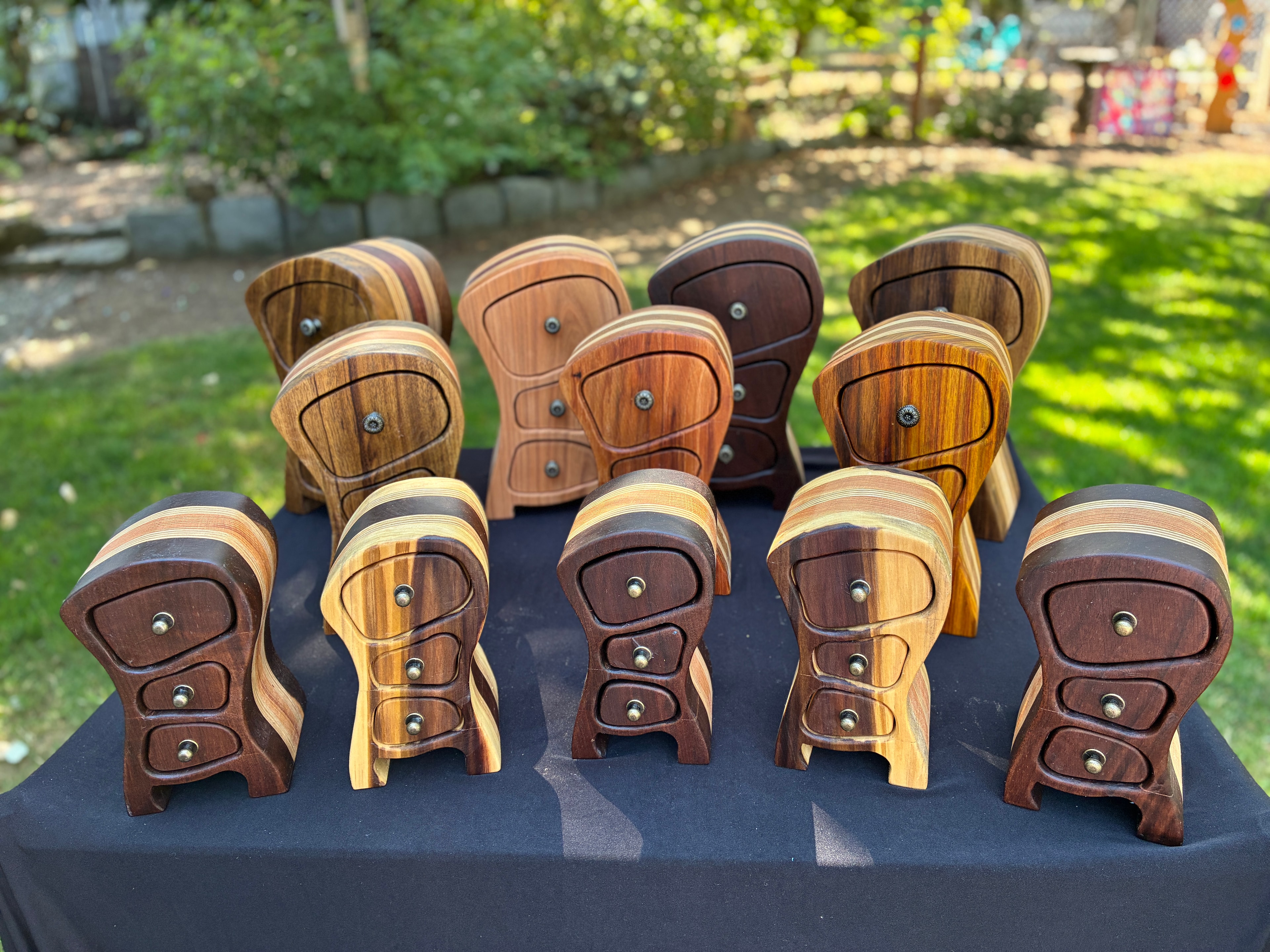 Collection of handcrafted wooden jewelry boxes displayed on a table outdoors